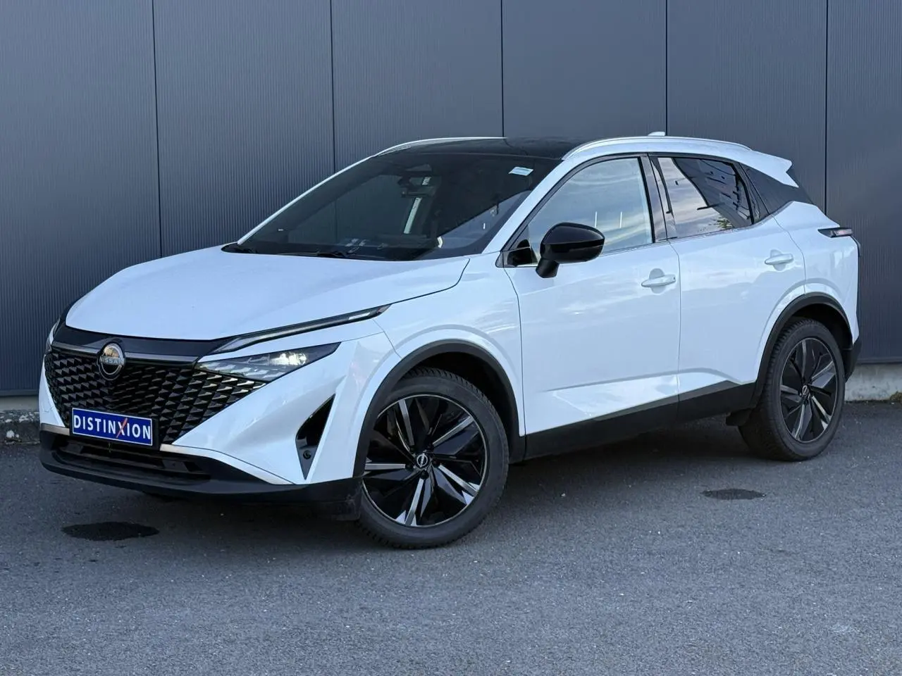 Nissan Qashqai blanc nacré en 3/4 avant droit, avec toit panoramique noir et jantes alliage noires.
