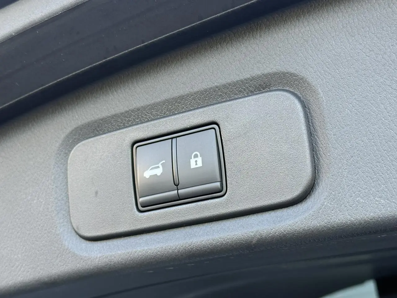 Gros plan sur les boutons d'ouverture électrique du hayon et de verrouillage dans l'habitacle du Nissan Qashqai blanc nacré.