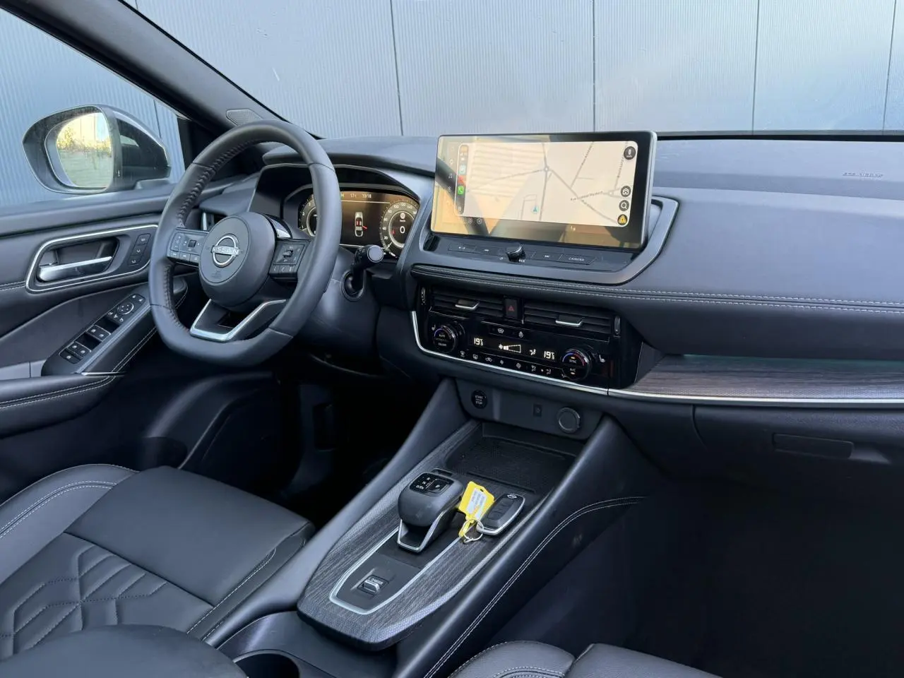 Intérieur noir du Nissan Qashqai 2025 vu côté conducteur, avec écran tactile GPS et volant cuir multifonctions.