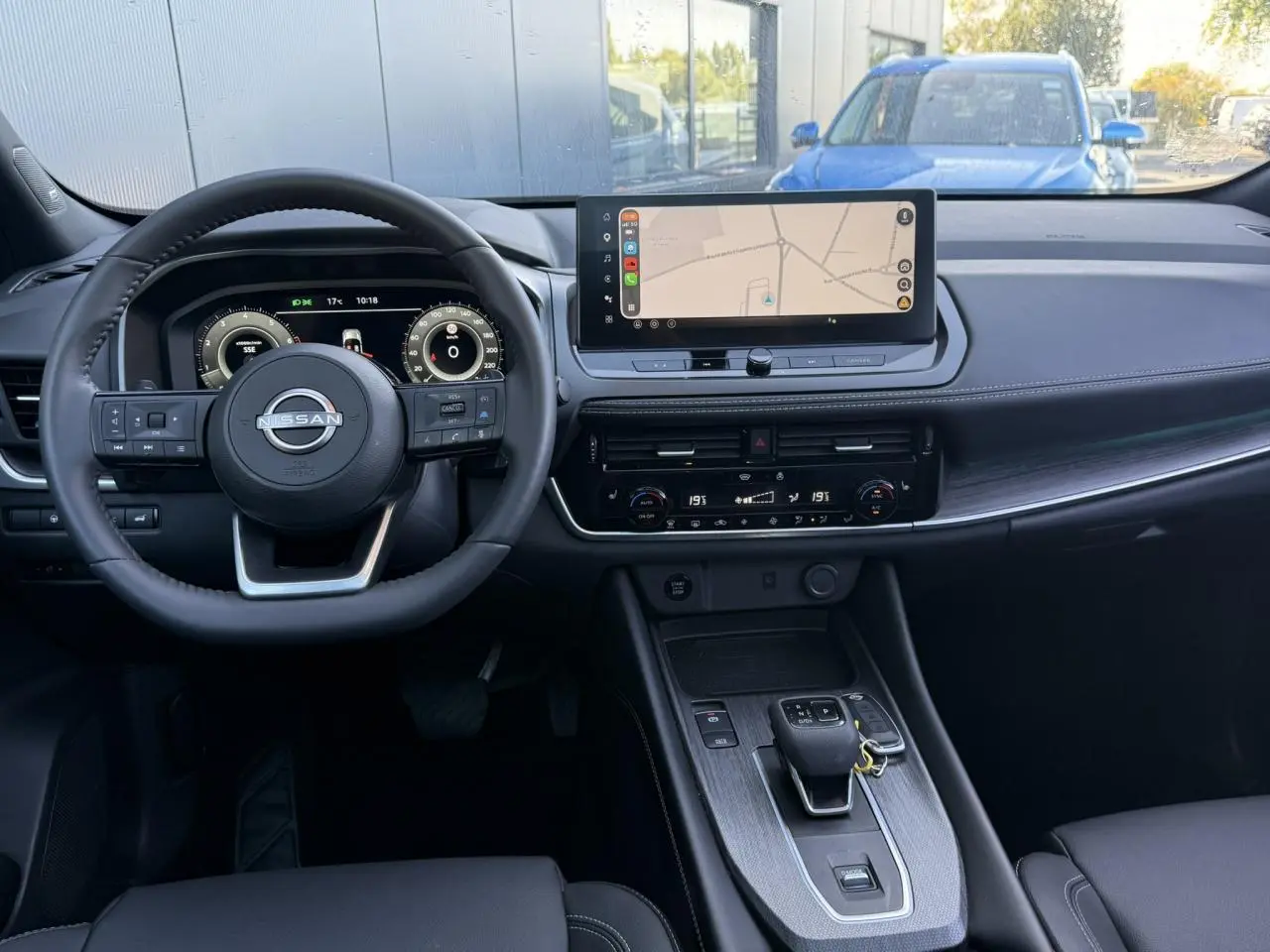 Vue intérieure frontale du tableau de bord du Nissan Qashqai 2025 avec écran tactile GPS et volant cuir noir.