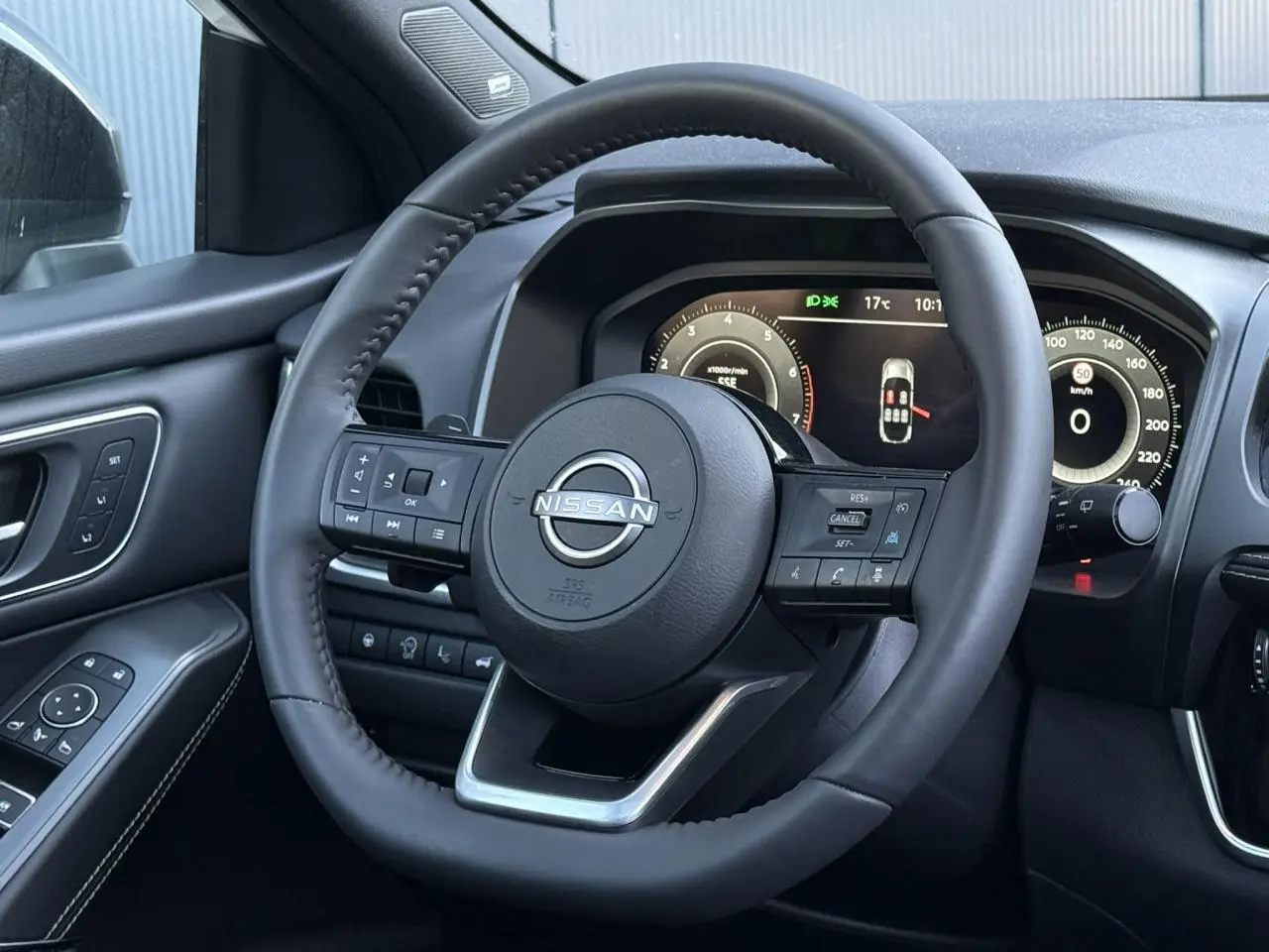Vue intérieure centrée sur le volant cuir noir du Nissan Qashqai 2025 avec tableau de bord numérique et commandes intégrées.