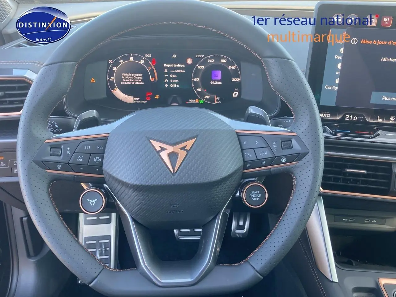 Vue frontale du volant sport en cuir perforé noir avec logo CUPRA et tableau de bord numérique lumineux.