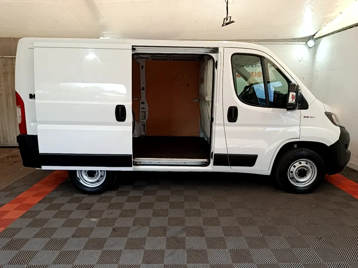 Vue latérale gauche d’un FIAT Ducato Fourgon blanc 2021 avec porte coulissante ouverte montrant l’espace de chargement.
