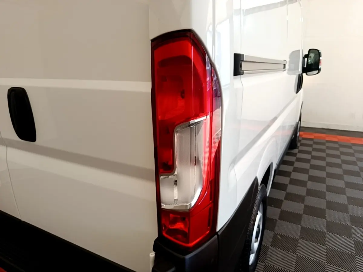 Vue arrière côté droit du FIAT Ducato Fourgon blanc, mettant en valeur le feu arrière et la porte latérale coulissante.