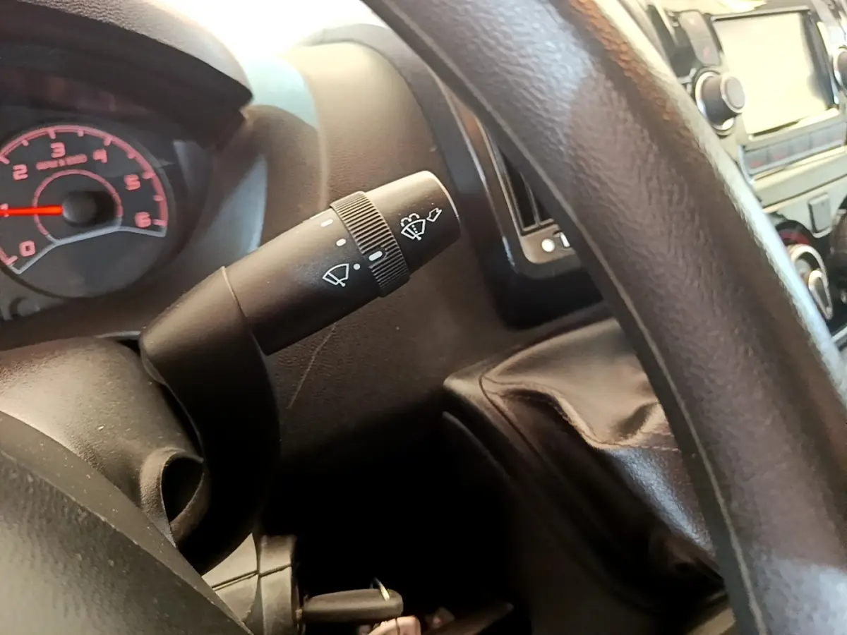 Gros plan sur la commande d’essuie-glace à gauche du volant dans l’habitacle du Fiat Ducato Fourgon blanc.