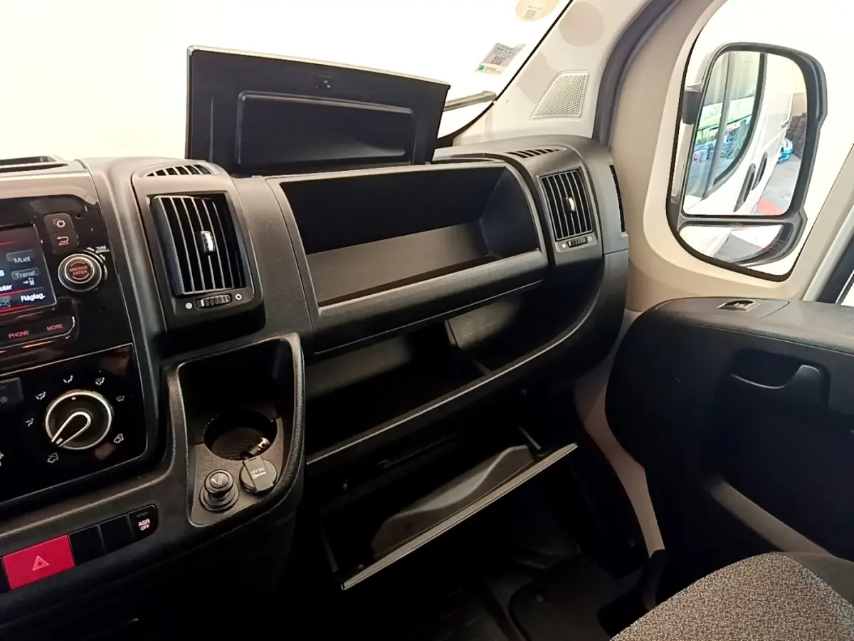 Vue intérieure côté passager du tableau de bord noir et des rangements ouverts du Fiat Ducato Fourgon blanc 2021.