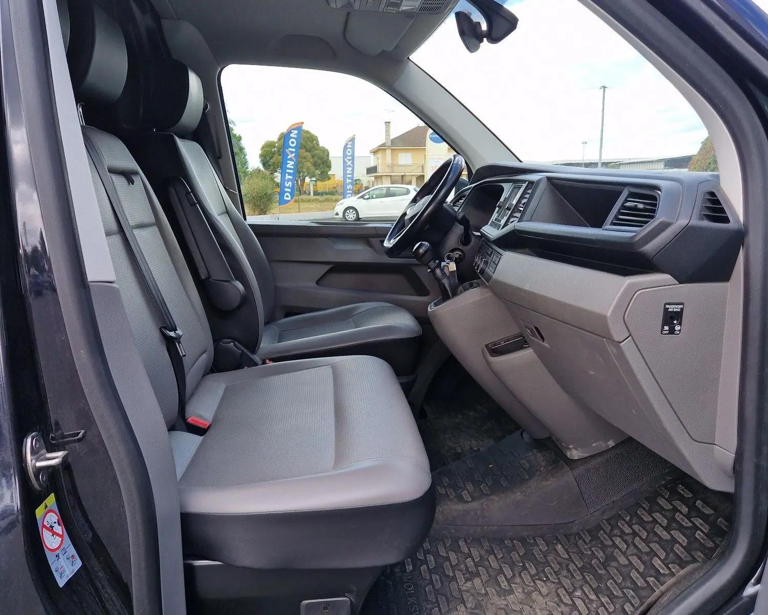 Vue intérieure côté conducteur du Volkswagen Transporter noir 2020, montrant sièges gris et tableau de bord moderne.