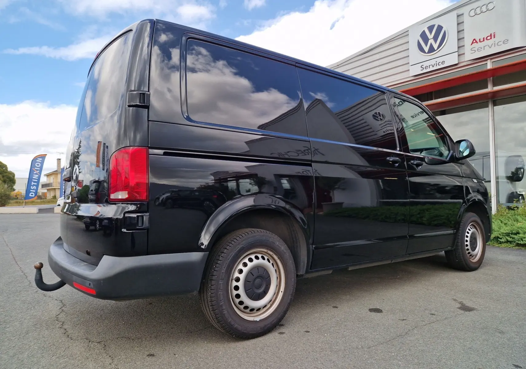 Vue 3/4 arrière droite d'un Volkswagen Transporter noir 2020 avec attelage rigide et vitres teintées.