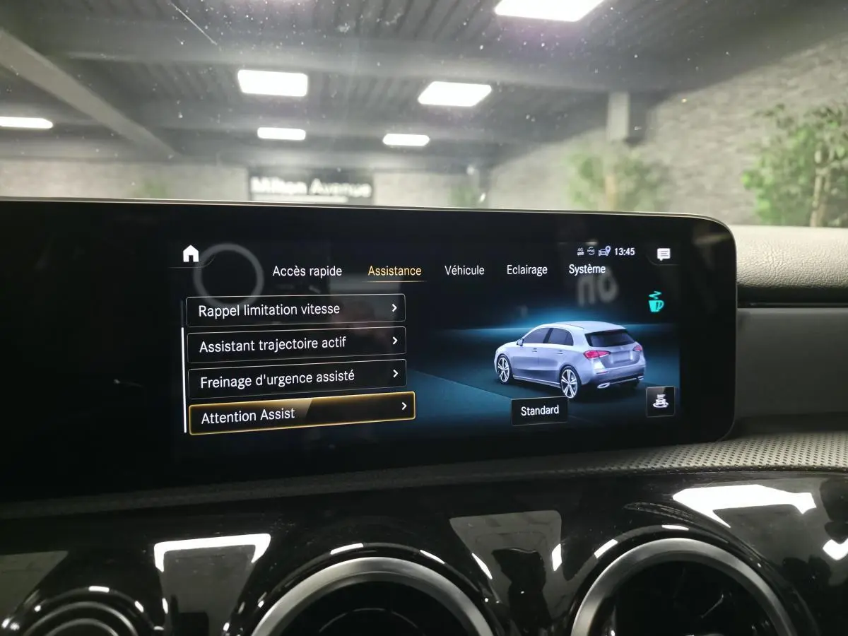Écran multimédia affichant les aides à la conduite et une illustration grise côté droit de la Mercedes Classe A AMG Line.