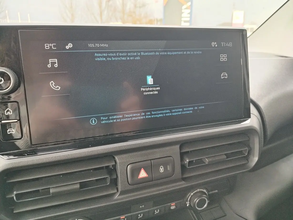 Vue rapprochée de l'écran tactile central et de la console de la Peugeot Partner Fourgon blanc Icy, avec commandes de climatisation visibles.