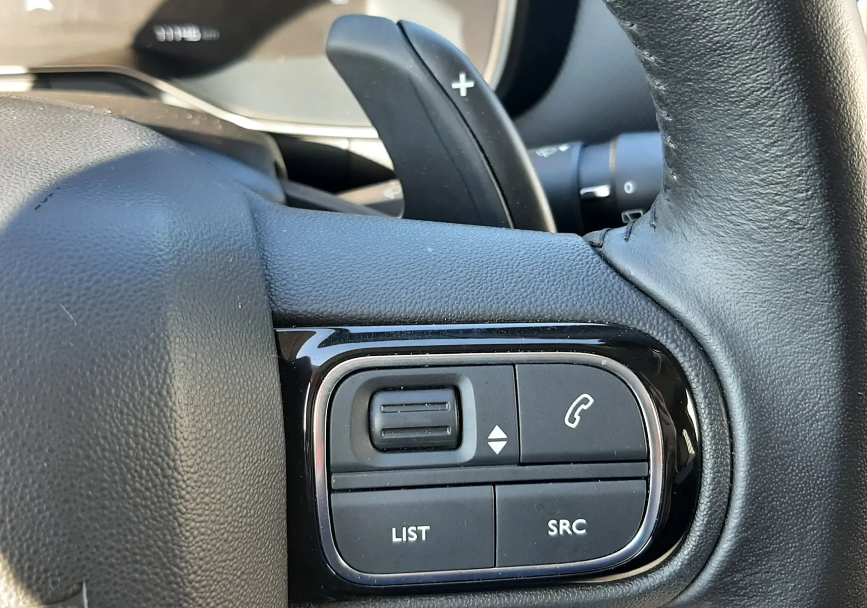 Gros plan sur les commandes multifonctions côté gauche du volant en cuir noir du Citroën C5 Aircross 2024.