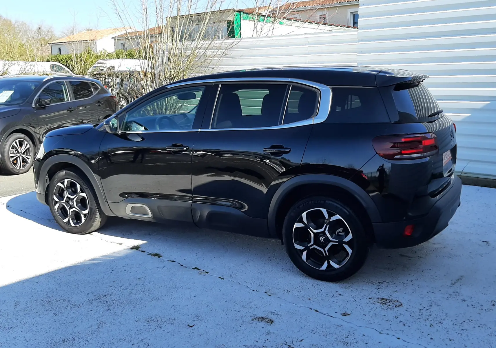 Vue de profil côté gauche d'un Citroën C5 Aircross noir Perla Nera 2024 avec jantes bicolores et détails gris sur les bas de caisse.