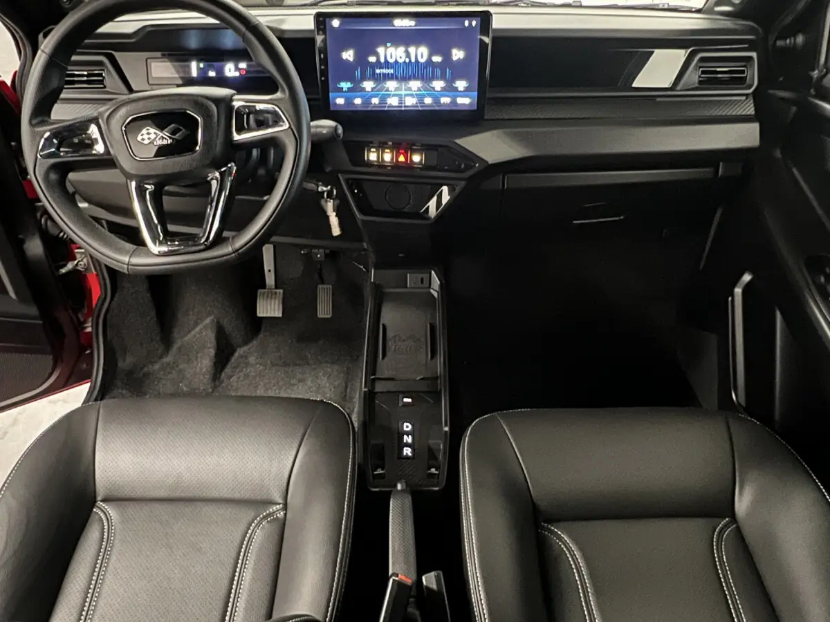 Vue intérieure avant de la LIGIER JS50 BEV 8KWH ELITE avec tableau de bord numérique et écran tactile central.