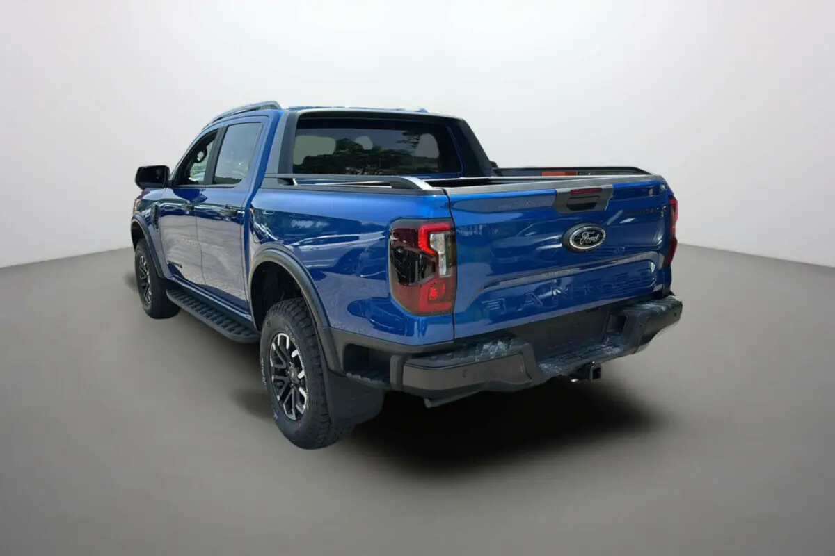 Ford Ranger 205 Wildtrak X Pack X Rideau bleu lightning, vue 3/4 arrière droit avec barres de toit et jantes alu noires.