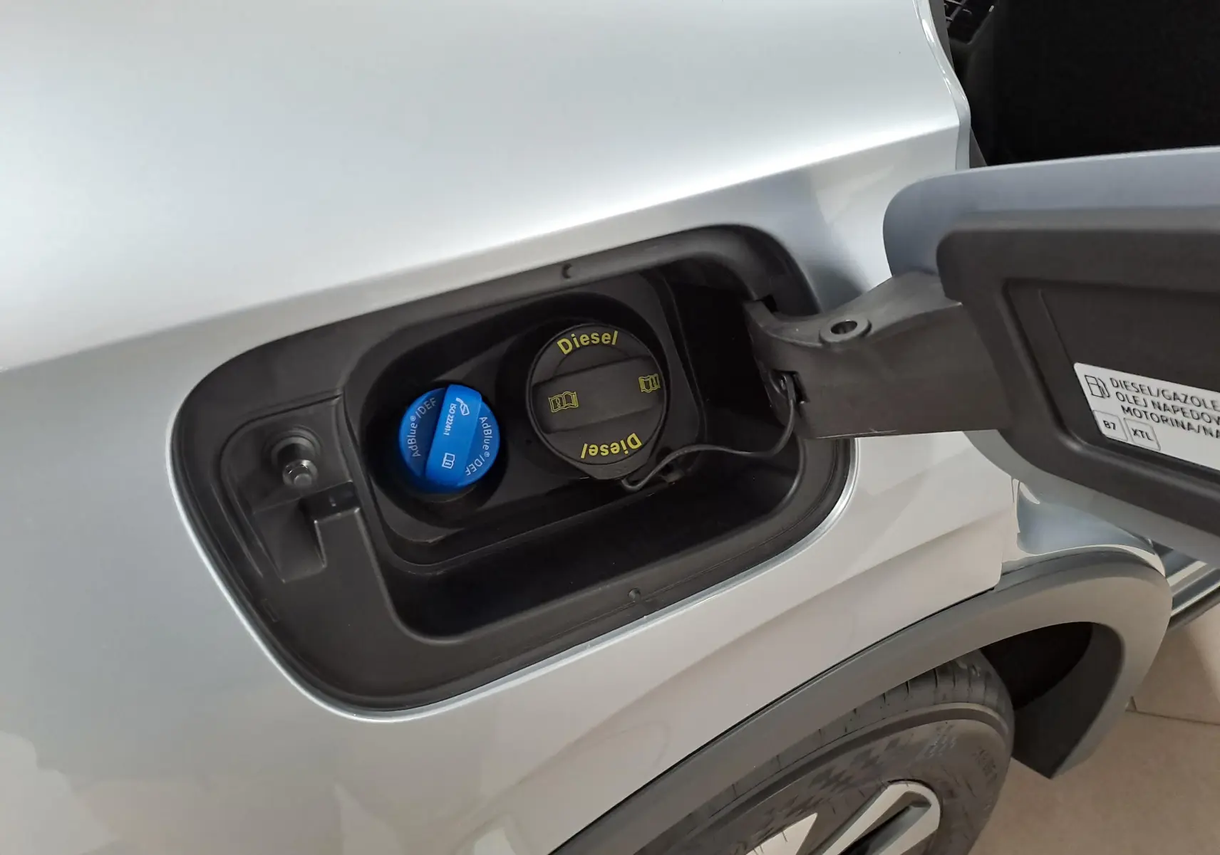 Gros plan sur la trappe à carburant côté gauche du Volkswagen Tiguan 2025 argent Dolomite avec bouchons Diesel et AdBlue visibles.