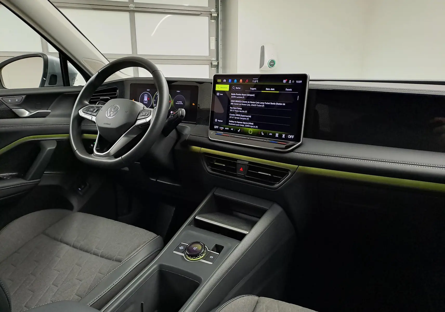 Vue intérieure côté conducteur du Volkswagen Tiguan 2025, avec tableau de bord noir et écran tactile central lumineux.