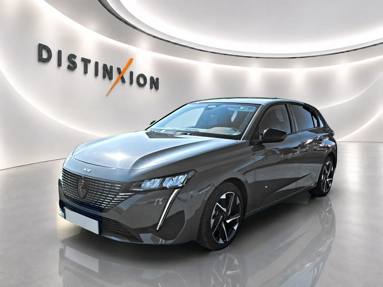 Peugeot 308 gris 3/4 avant droit dans un showroom lumineux avec jantes alliage et signature lumineuse LED.