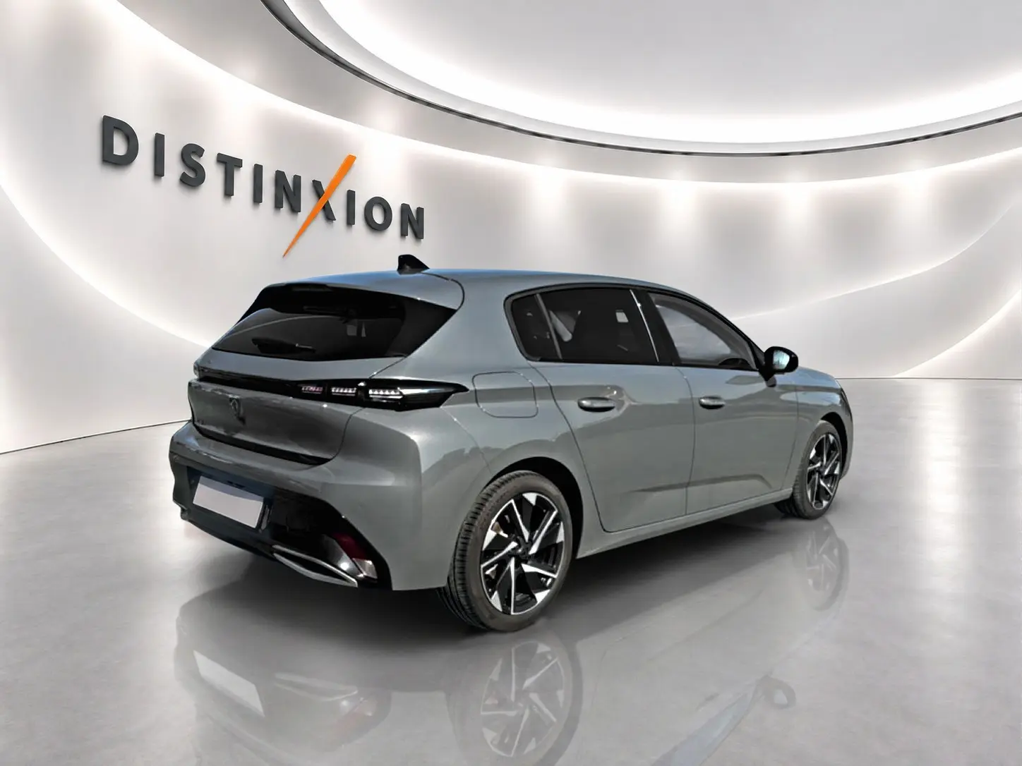 Peugeot 308 gris en vue 3/4 arrière droit, jantes alliage noires et vitres arrière surteintées dans un studio lumineux.