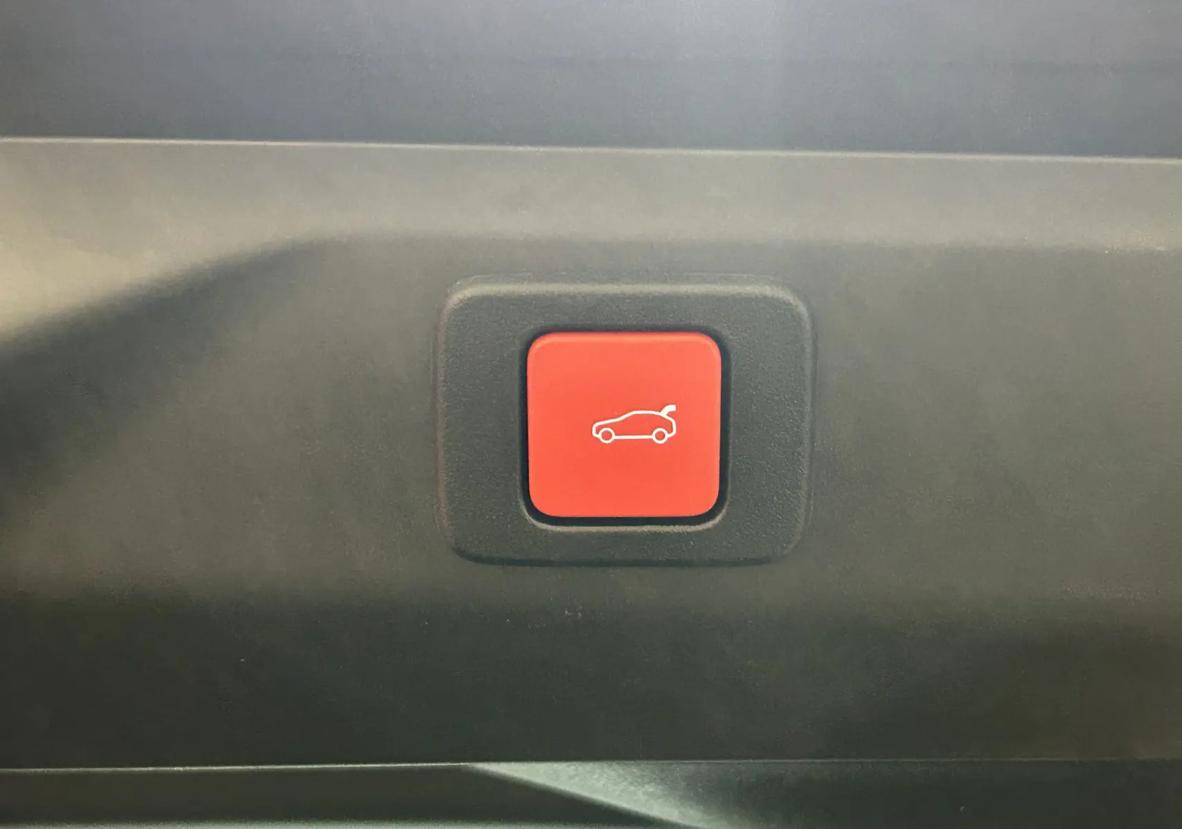 Bouton rouge d'ouverture électrique du hayon sur le panneau intérieur d'un Peugeot 3008 blanc Okenite.