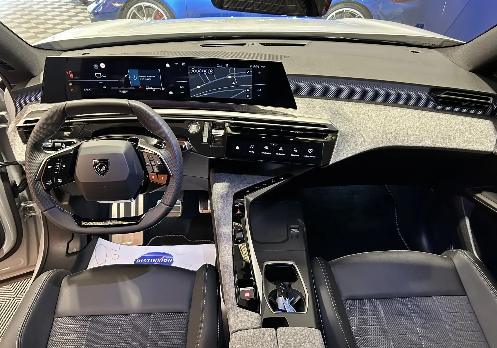Vue intérieure avant du Peugeot 3008 blanc Okenite 2025, mettant en valeur le tableau de bord numérique et le volant multifonction.