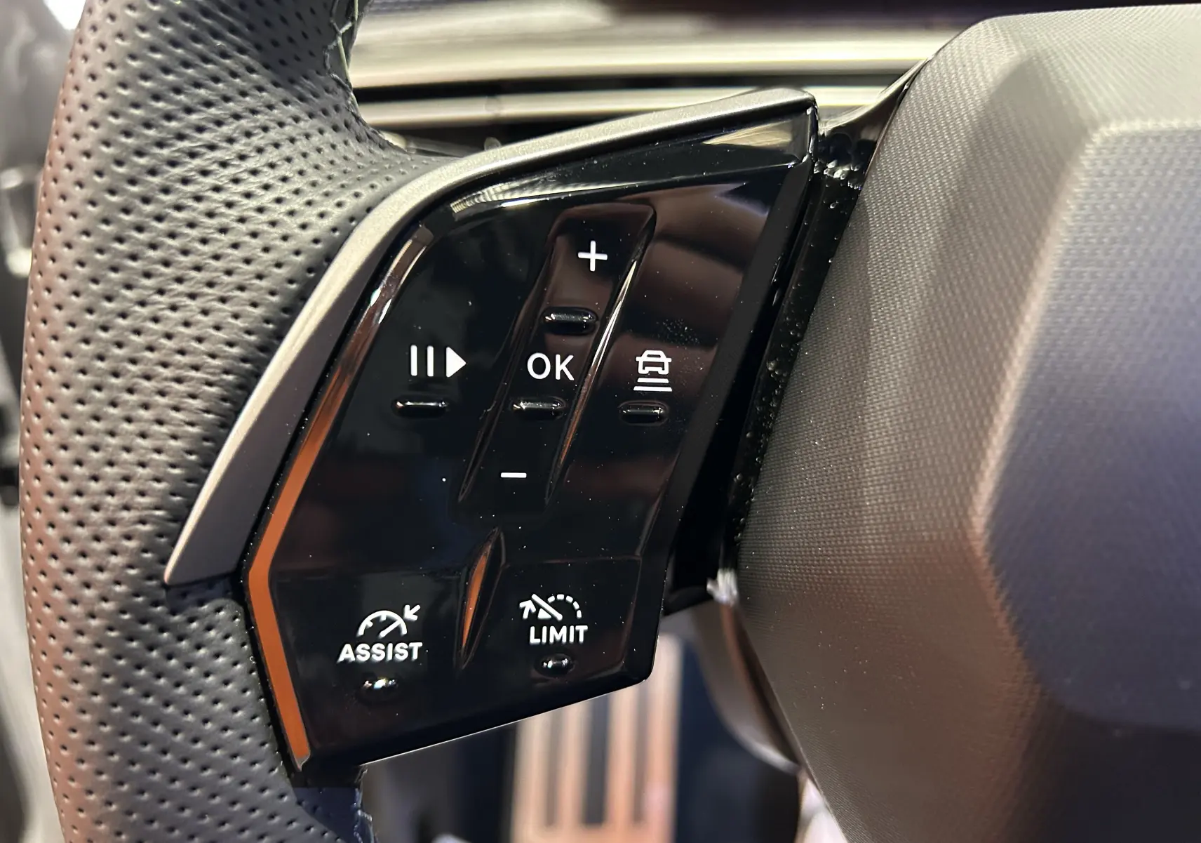 Gros plan sur les commandes noires du volant côté gauche du Peugeot 3008 III Hybrid 145, avec boutons multifonctions.