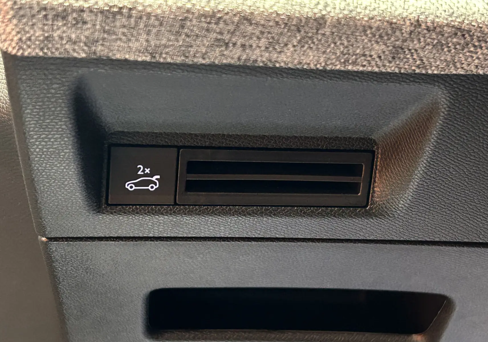 Gros plan sur le bouton d'ouverture électrique du hayon dans l'habitacle du Peugeot 3008 blanc Okenite.