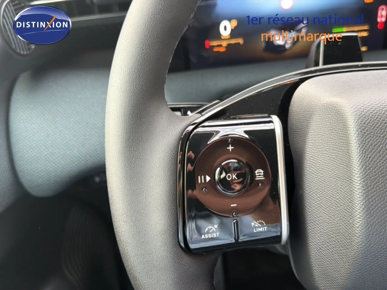 Gros plan sur la commande multifonction gauche du volant gris du Citroën C5 Aircross Hybrid 2026, avec affichage numérique en arrière-plan.