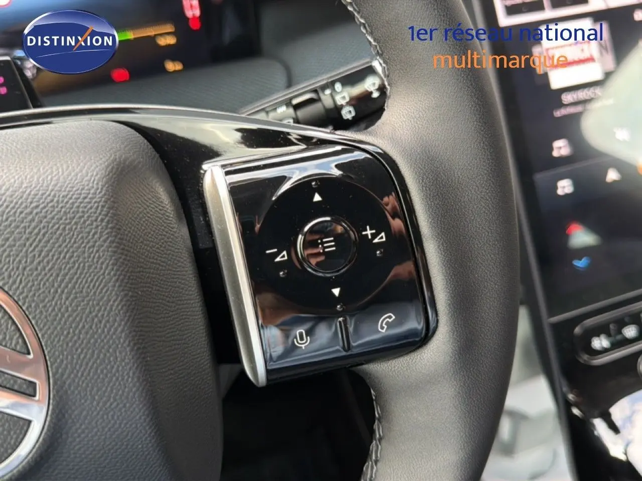 Gros plan sur les commandes gauche du volant en cuir noir du Citroën C5 Aircross Hybrid gris platinium, avec écran tactile en arrière-plan.
