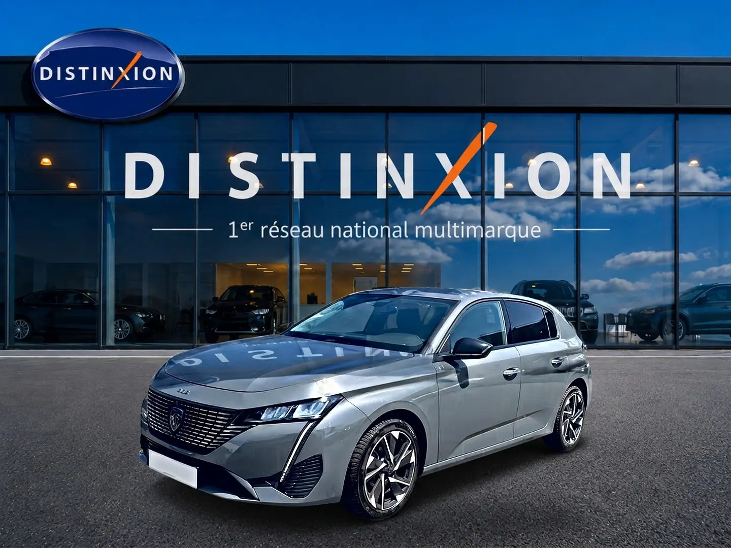 Peugeot 308 gris vue 3/4 avant droit, avec calandre distinctive et jantes alliage modernes, devant showroom Distinxion.