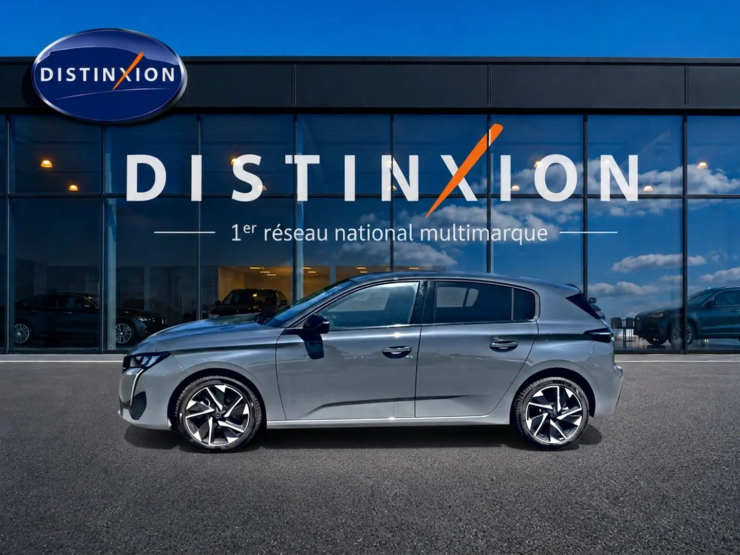 Profil côté gauche d'une Peugeot 308 gris métallisé 2025 avec jantes alliage modernes, devant une vitrine Distinxion.