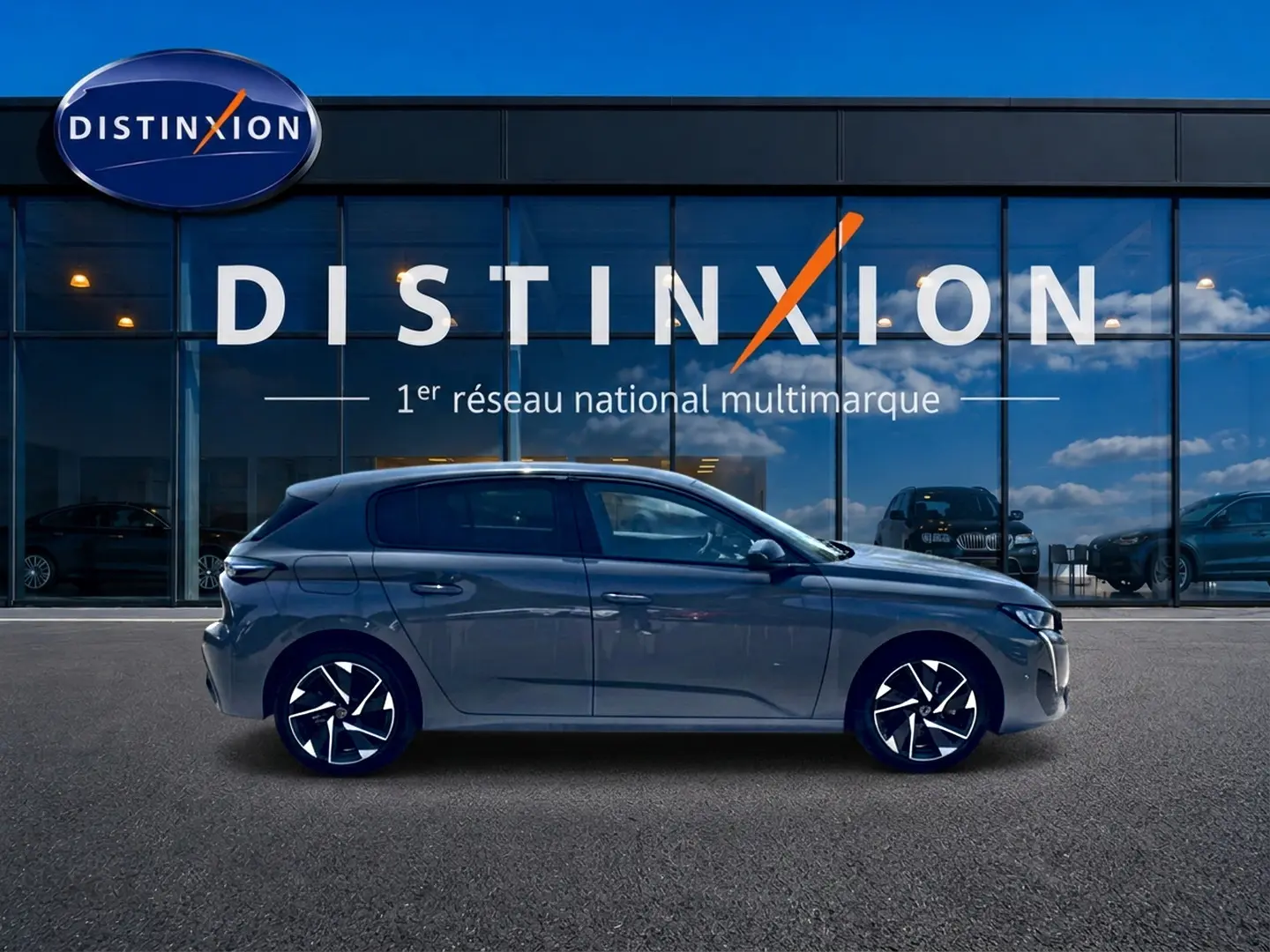 Profil côté gauche d'une Peugeot 308 gris 2025 avec jantes alu noires et design moderne devant une vitrine Distinxion.