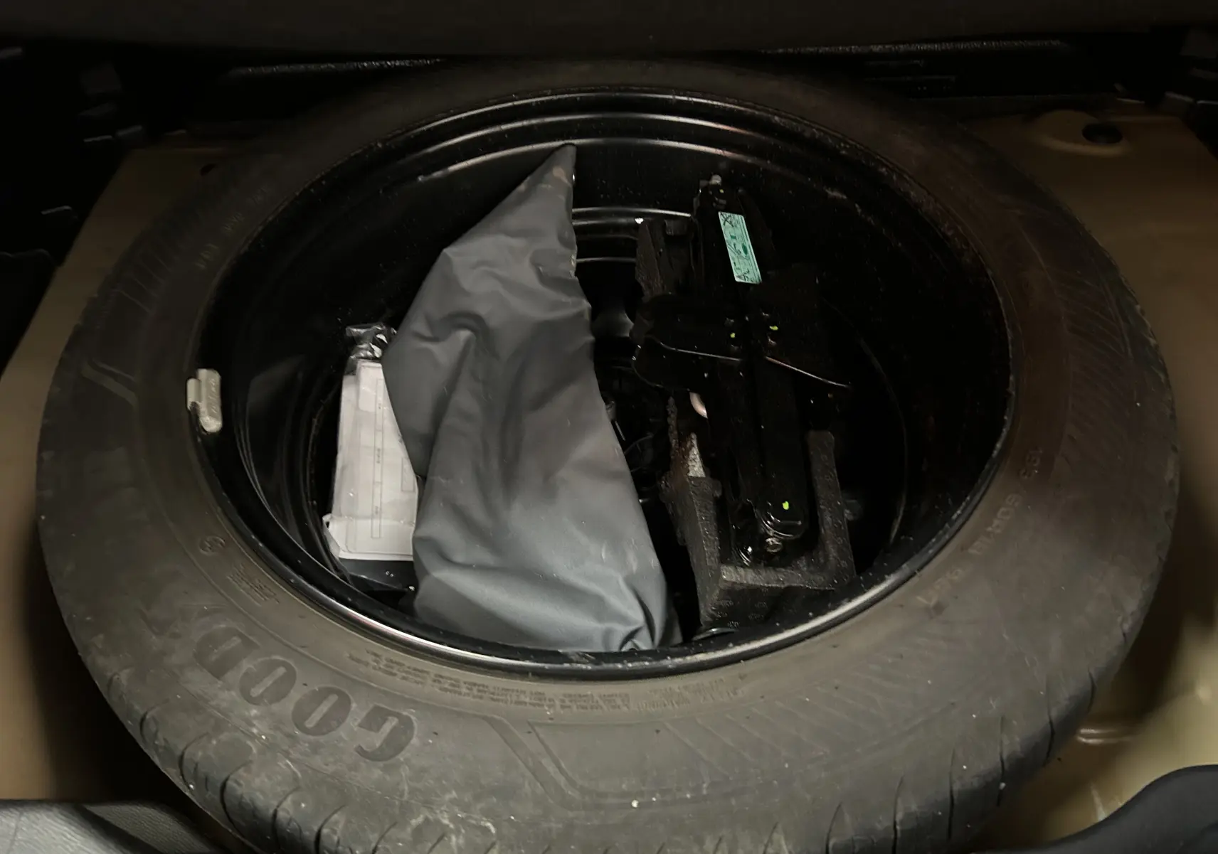 Roue de secours Goodyear avec outillage et housse grise dans le coffre d'une Citroën C4 PureTech 100 Feel orange.