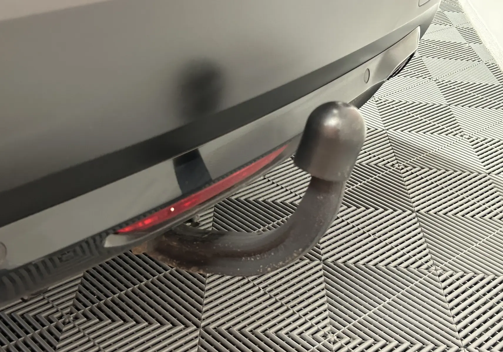 Gros plan sur l'attelage arrière noir du Citroën C4 orange PureTech 100 Feel de 2021, avec caméra de recul visible.