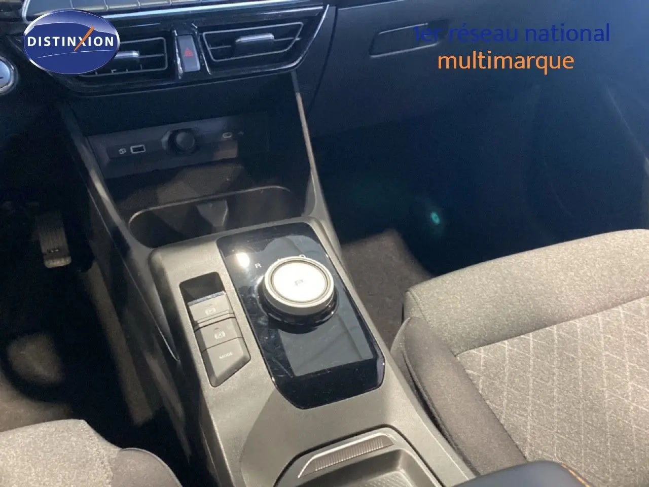 Vue rapprochée de la console centrale de la MG3 1.5L Hybrid+ 2024 avec molette de boîte auto et sièges tissu gris.
