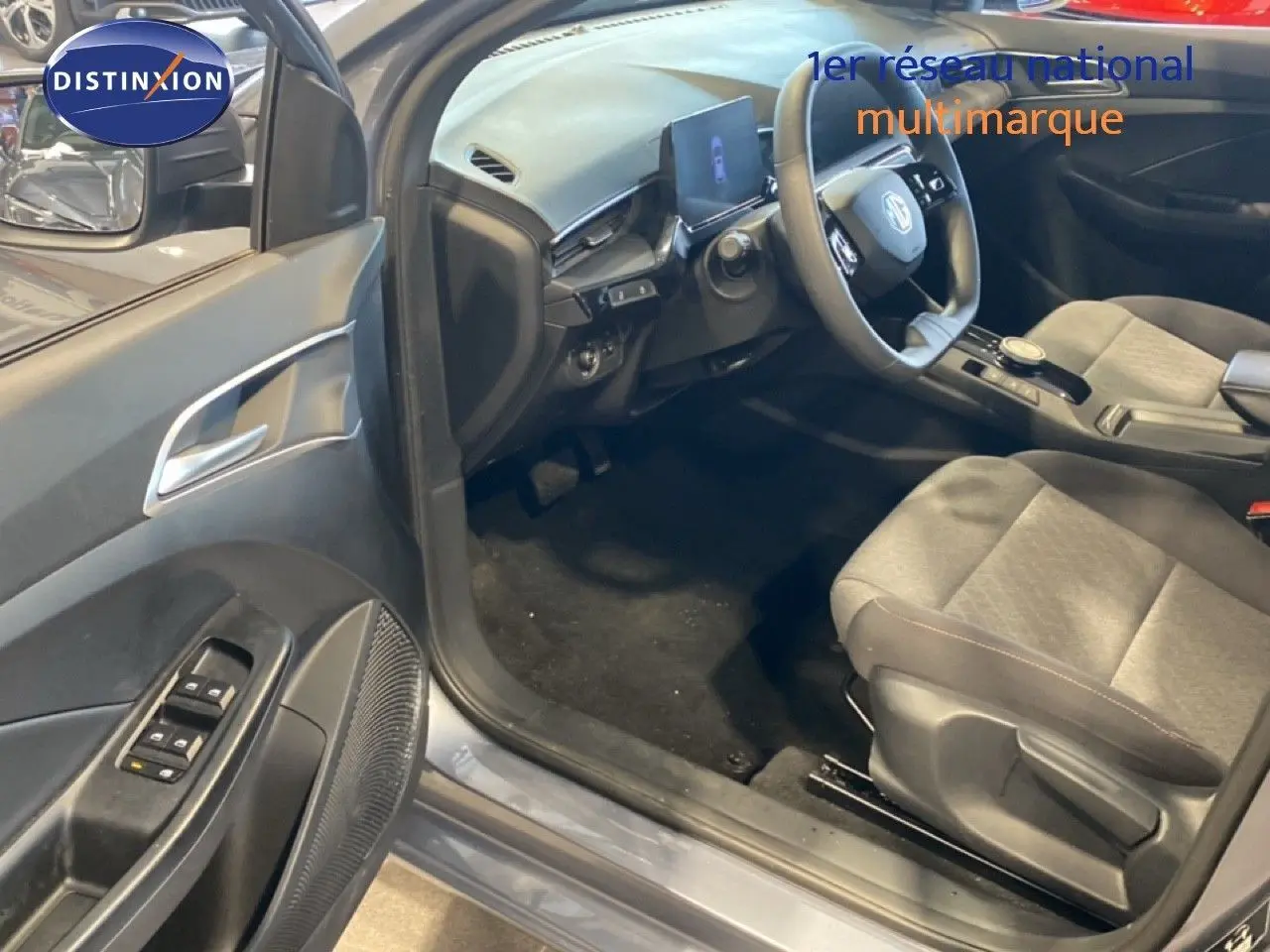 Vue intérieure côté conducteur de la MG3 1.5L Hybrid+ 2024 en gris Hampstead, avec sièges tissu gris et tableau de bord moderne.