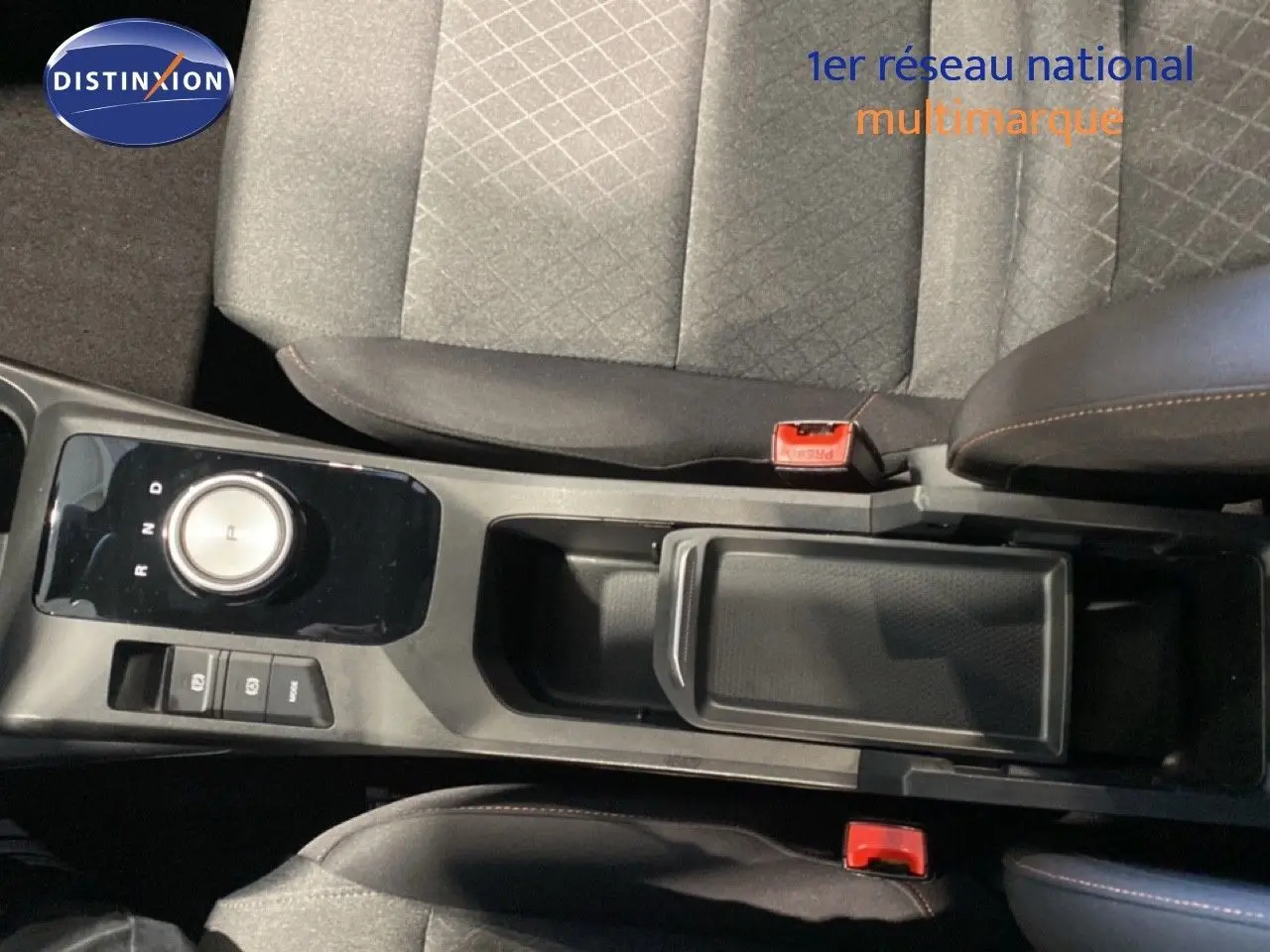 Vue intérieure centrée sur la console centrale et le levier rotatif de la MG3 1.5L Hybrid+ en tissu gris et noir.