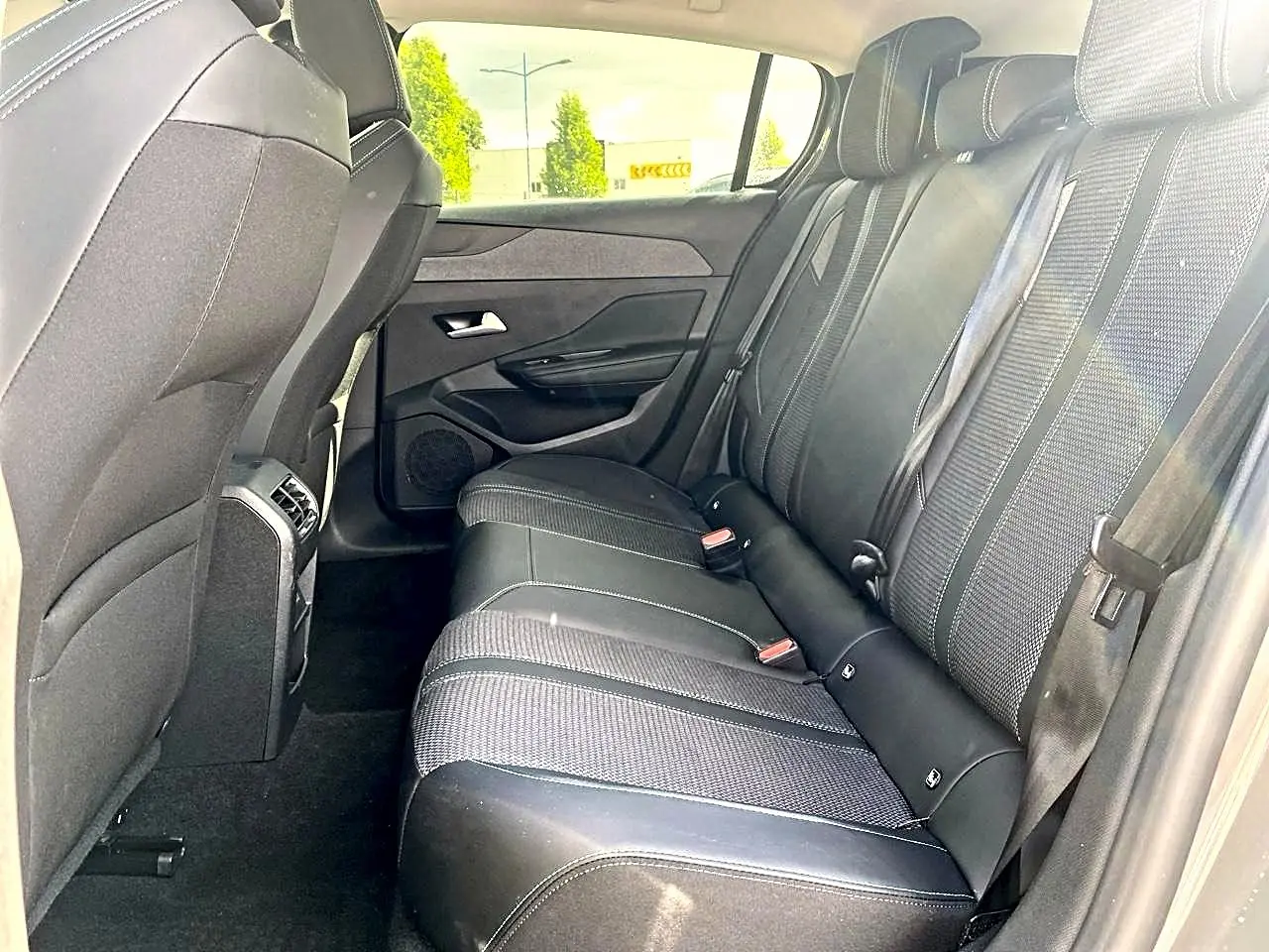 Vue latérale droite de l'habitacle arrière d'une Peugeot 308 gris, montrant la banquette et les appuie-têtes noirs.