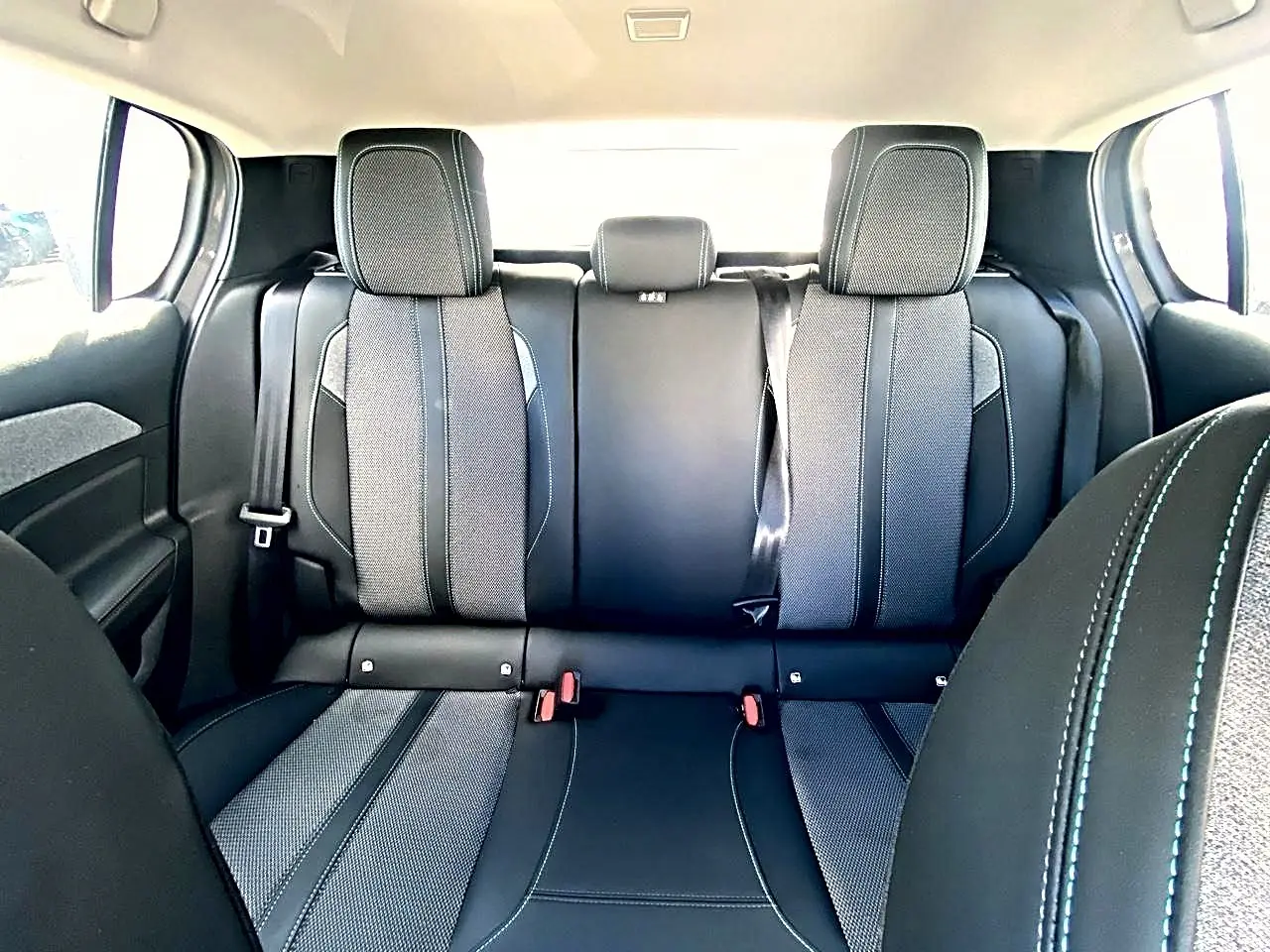 Vue arrière intérieure de la banquette arrière noire et grise de la Peugeot 308 2025 avec ceintures de sécurité visibles.