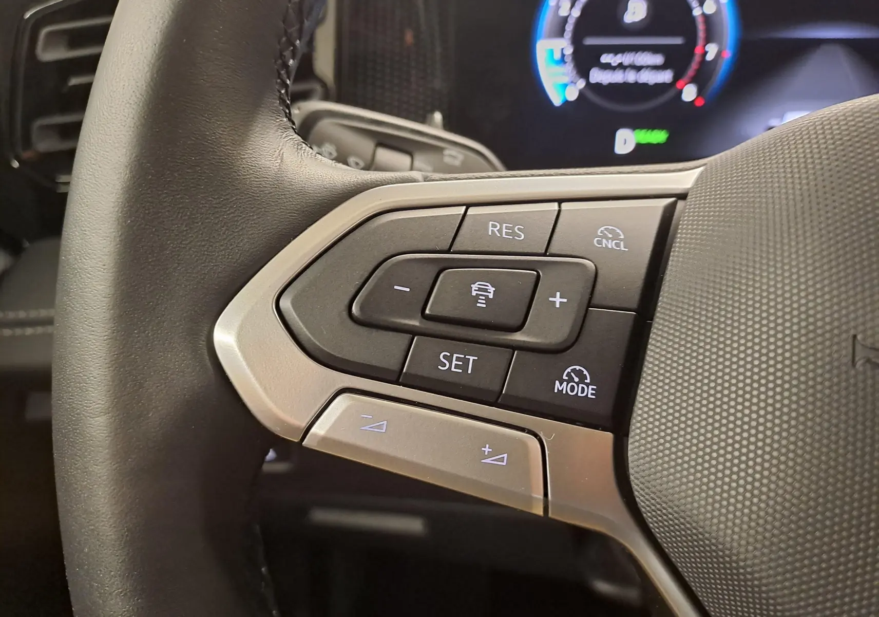 Gros plan sur les commandes à gauche du volant du Volkswagen Tiguan 2024, avec boutons de régulateur de vitesse et assistant de conduite.