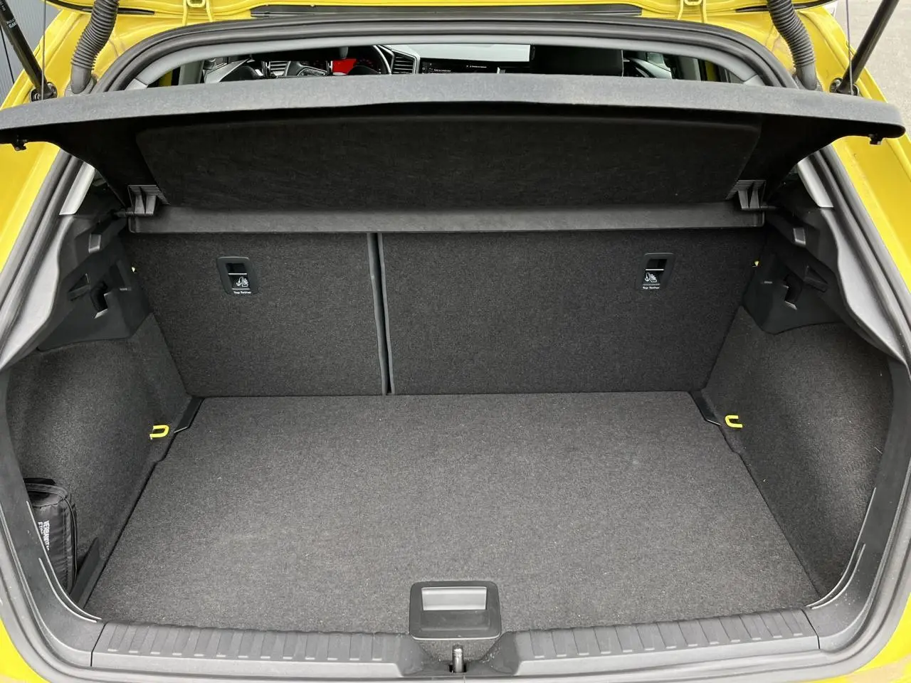 Coffre ouvert vu de l'arrière d'une Audi A1 Allstreet jaune Python, montrant un espace de chargement propre et spacieux.