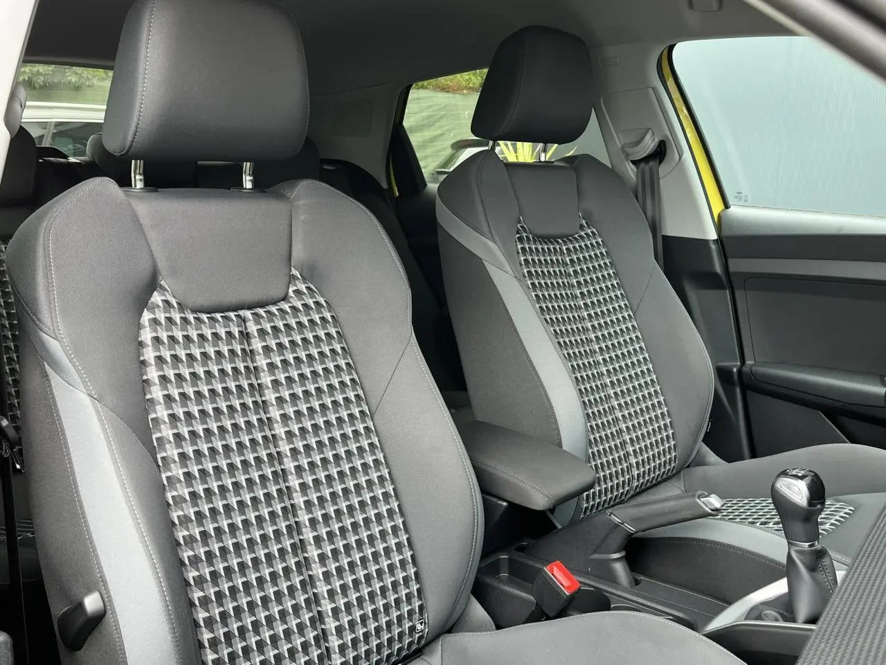 Gros plan sur les sièges sport gris à motifs géométriques de l'Audi A1 Allstreet jaune Python, avec accoudoir central visible.