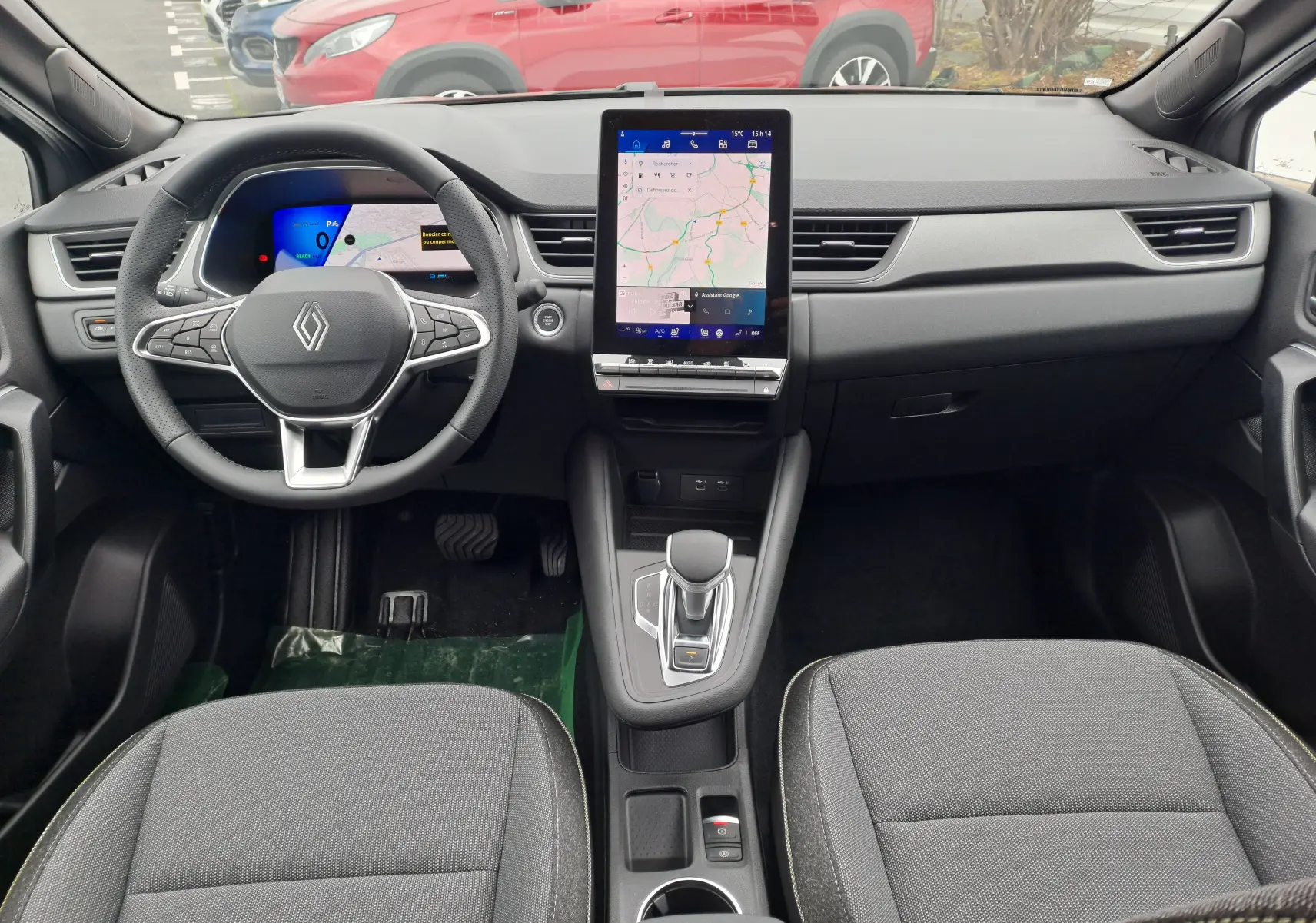 Intérieur Renault SYMBIOZ 2024, vue frontale du tableau de bord avec écran tactile vertical et sièges tissu gris.