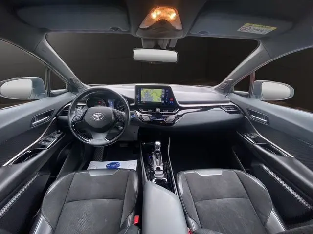 Vue intérieure avant du Toyota C-HR Hybride 2018, tableau de bord noir avec écran tactile central et volant multifonction.