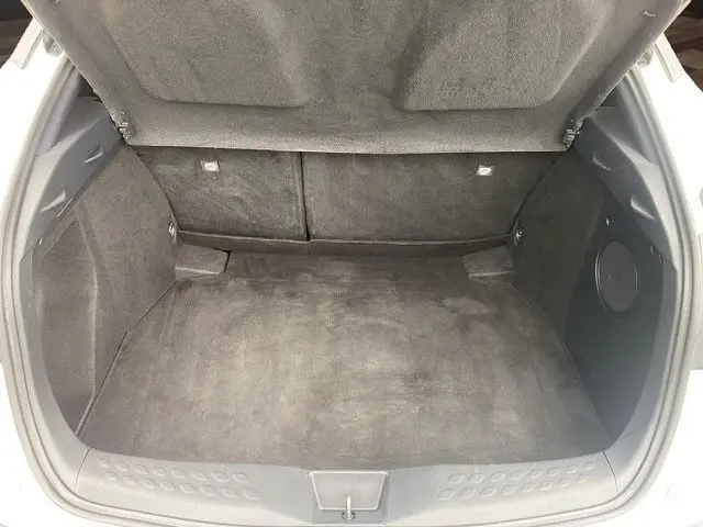 Coffre ouvert vu de l'arrière d'un Toyota C-HR Hybride blanc toit noir, montrant un espace de chargement propre et spacieux.