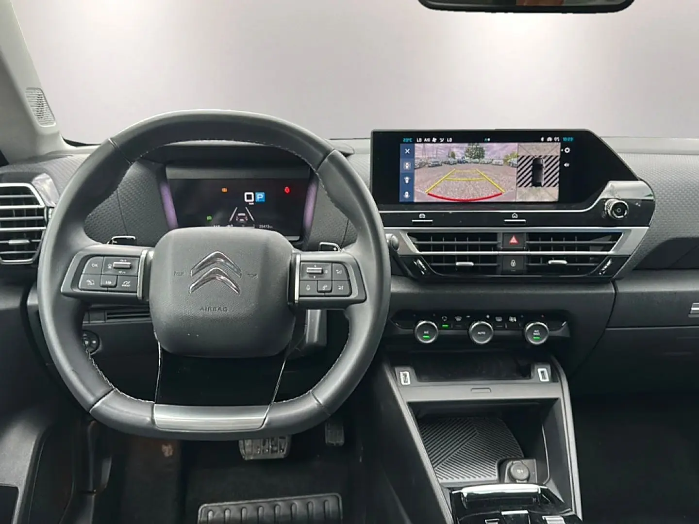 Vue intérieure frontale du tableau de bord et volant cuir noir de la Citroën C4 avec écran tactile affichant la caméra de recul.