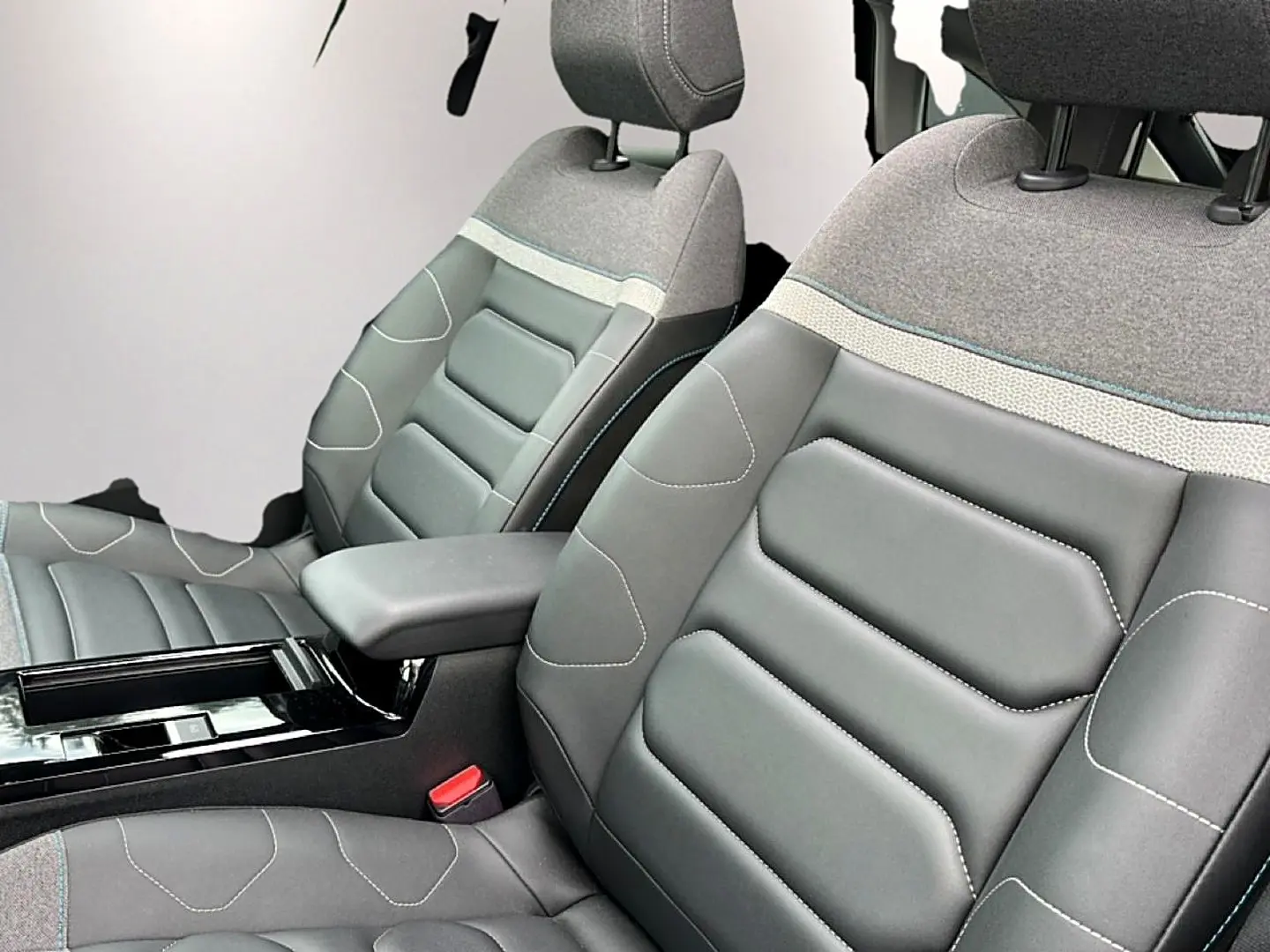 Gros plan sur les sièges avant gris cuir et tissu avec accoudoir central dans l'habitacle d'une Citroën C4 2024.