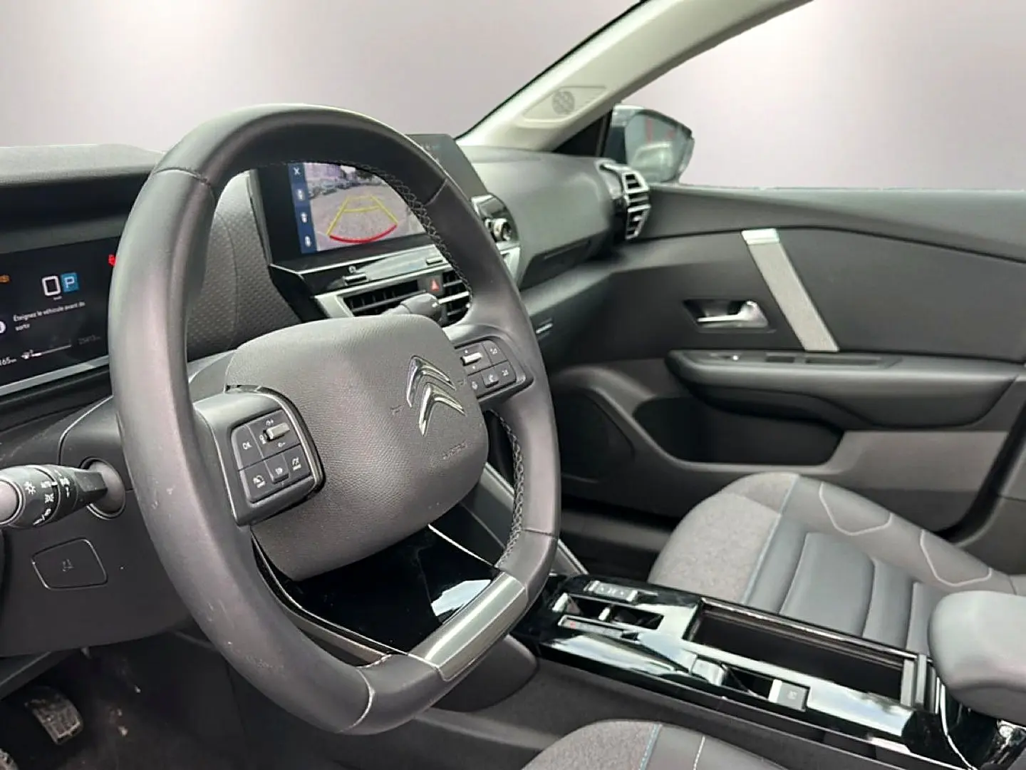 Intérieur de la Citroën C4 2024, vue côté conducteur sur le volant cuir et l’écran tactile avec caméra de recul.