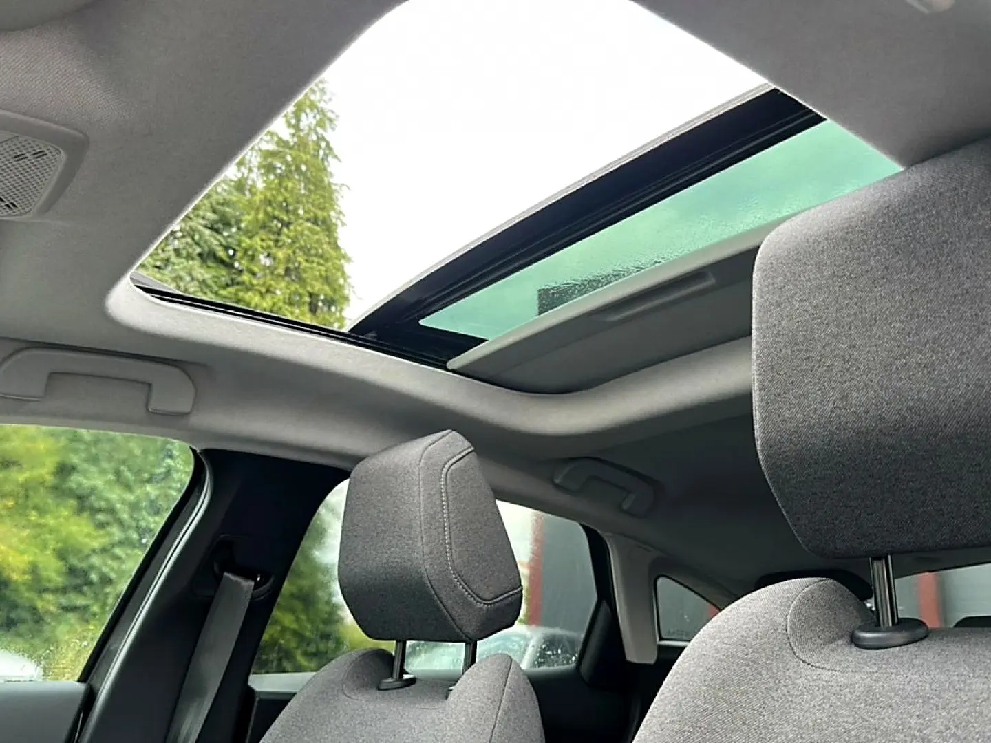 Vue intérieure montrant le toit ouvrant panoramique et les appuie-têtes avant en tissu gris d'une Citroën C4 2024.