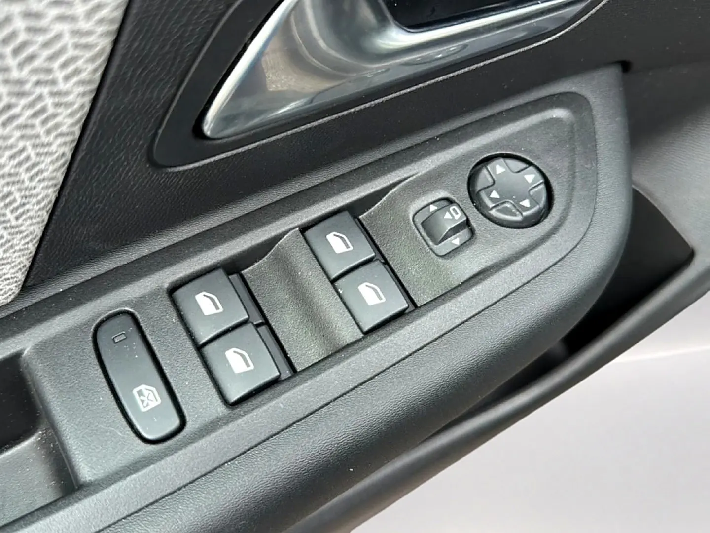 Gros plan sur les commandes de lève-vitres et rétroviseurs électriques côté conducteur d'une Citroën C4 gris 2024.