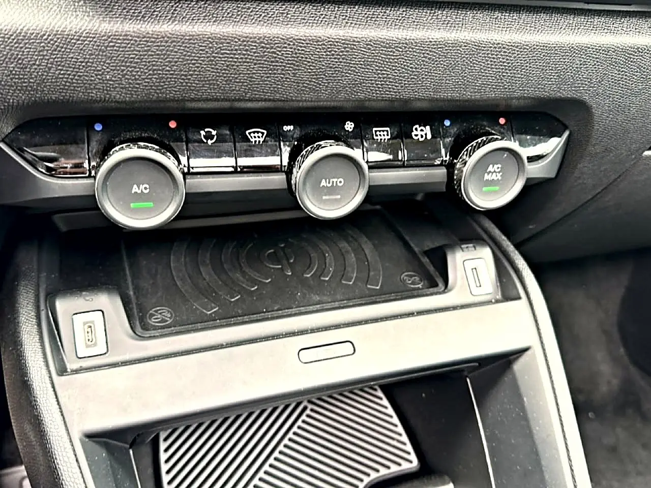 Détail de la console centrale avec commandes de climatisation et zone de recharge sans fil dans une Citroën C4 gris 2024.